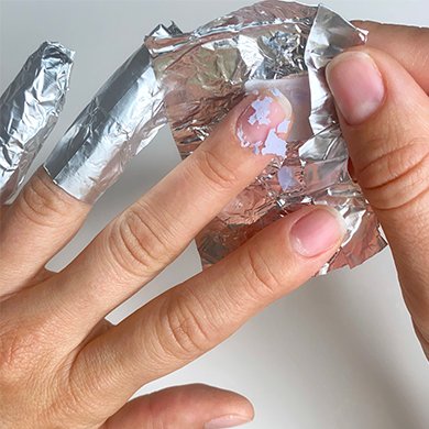 fingernail with flakes of purple gel polish