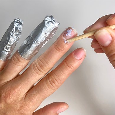 orangewood stick pushing remnants of gel polish off nail bed