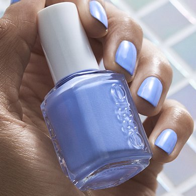 Model wearing purple nail polish holding don’t burst my bubble essie nail polish bottle.