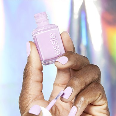 Model applying pink nail polish while holding in the you-niverse essie nail polish bottle.