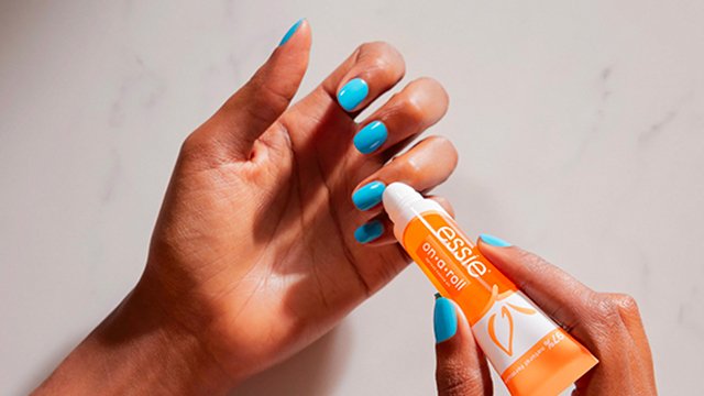 Model applying on-a-roll cuticle oil on light blue nails.