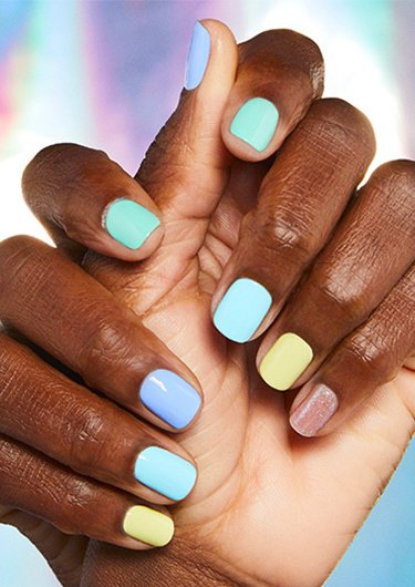 Deep skin tone model hands wearing different neon pastel nail color on each finger.