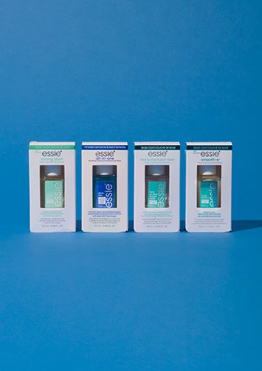 Row of four individually boxed bottles of essie base coats posed against a medium blue background