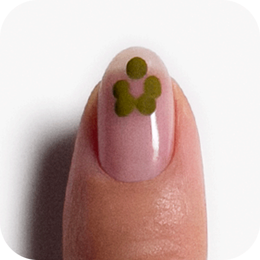 Nail painted with clear top coat and five dots of green nail polish in the upper center of the nail