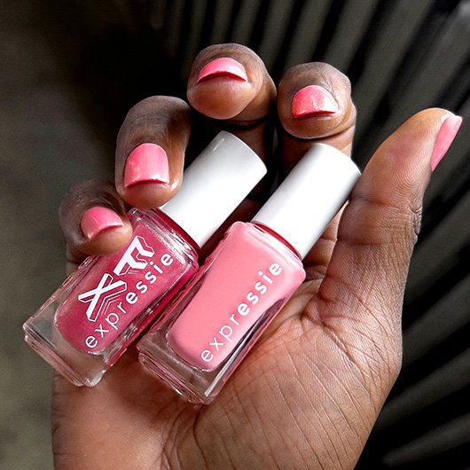 Dark skin model holding ethereal glow fx red and faux real fx pink bottles of essie expressie polish.