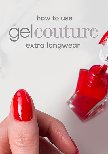 Thumb with nail painted in red beside a bottle of essie red nail polish