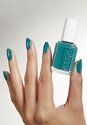 Close-up of a light skin hand with painted nails holding a bottle of nail polish in the same color