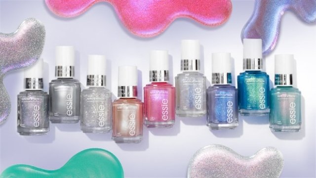 Close-up of a light skin hand with tattoos to which a second layer of nail polish is being applied